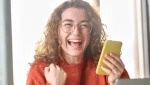 Moça comemorando feliz segurando celular